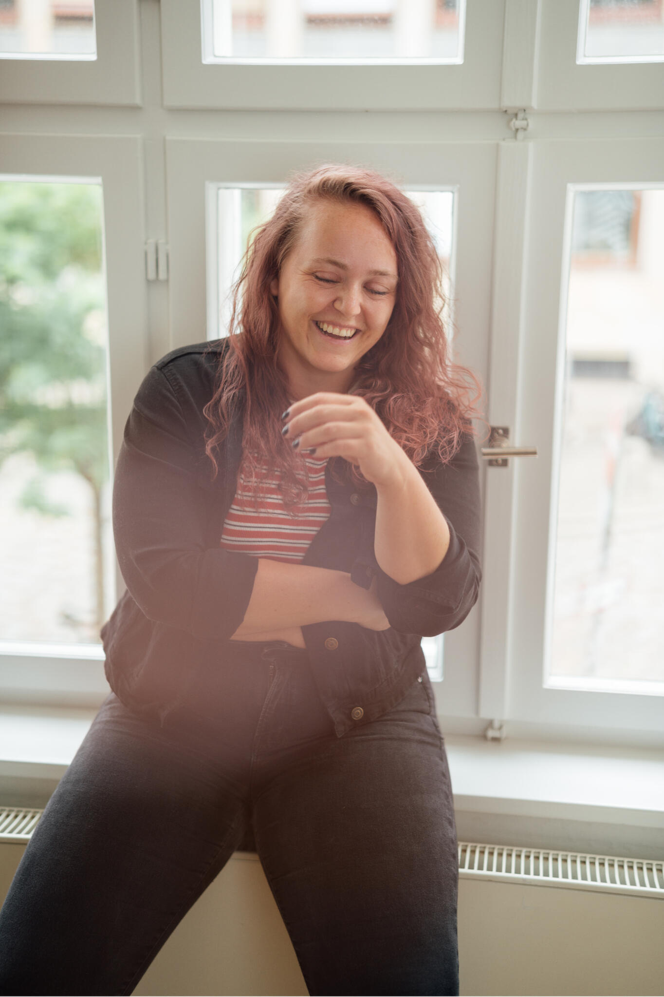 Rebecca sitzt auf einer Fensterbank und lacht
